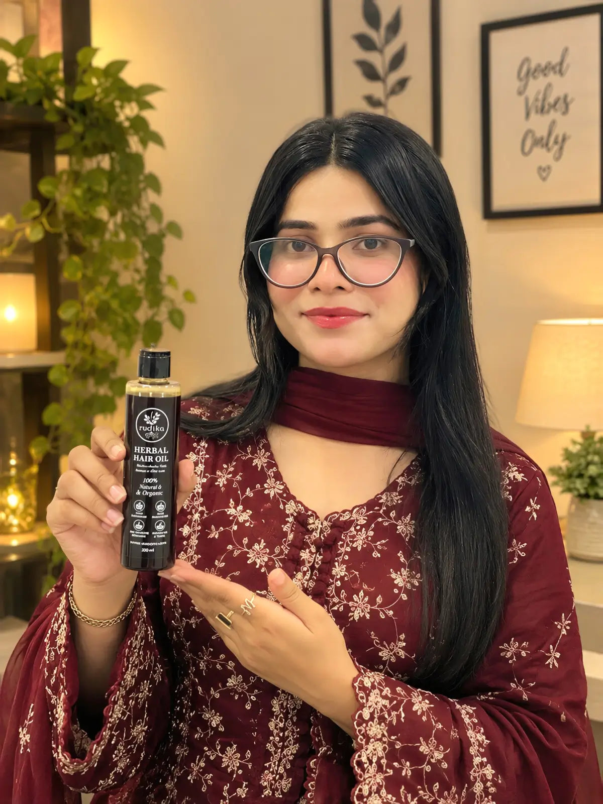 Woman in maroon holding Rootica Herbal Hair Oil 200ml