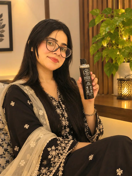 Woman in black holding Rootica Herbal Hair Oil 200ml